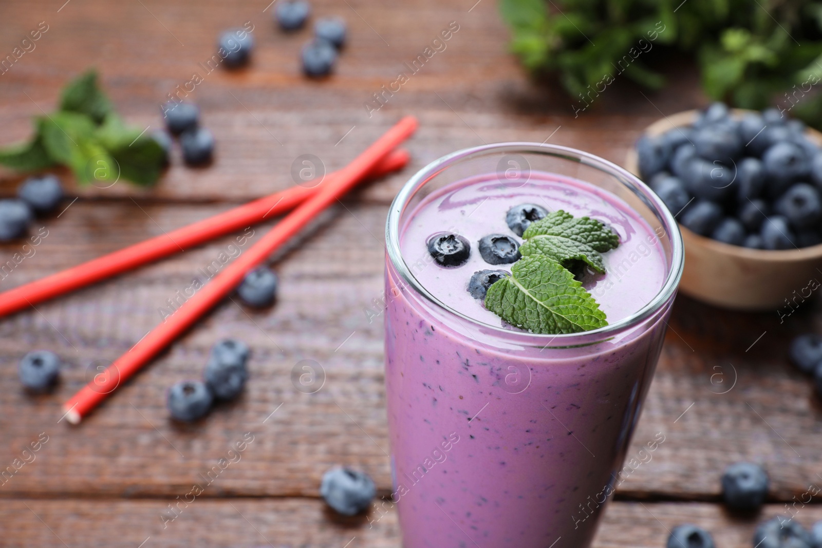 Photo of Glass of blueberry smoothie with mint on table, closeup. Space for text