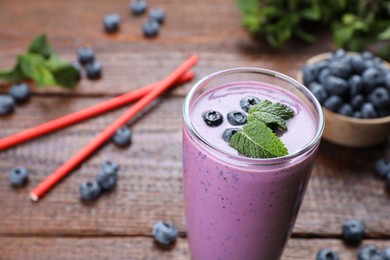 Photo of Glass of blueberry smoothie with mint on table, closeup. Space for text