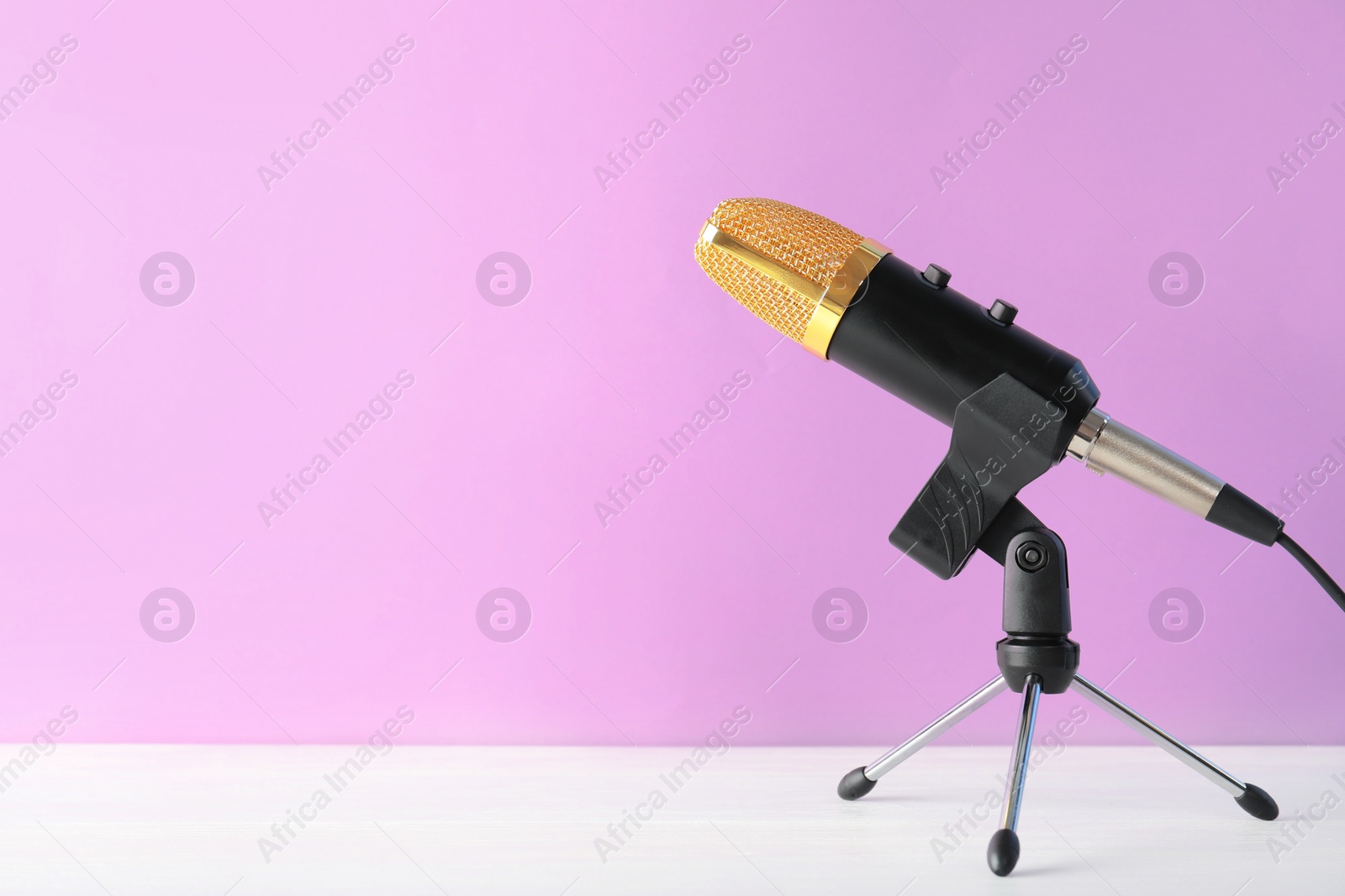 Photo of Microphone on table against color background. Space for text