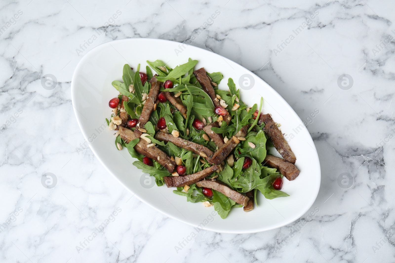 Photo of Delicious salad with beef tongue, arugula and seeds on white marble table, top view