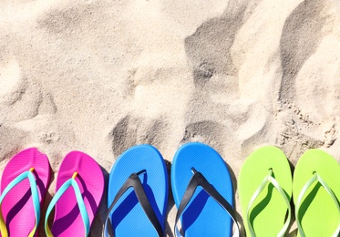 Photo of Flat lay composition with flip flops on sand in summer, space for text. Beach accessories