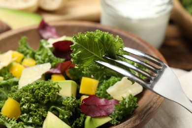 Photo of Delicious kale salad in wooden bowl, closeup