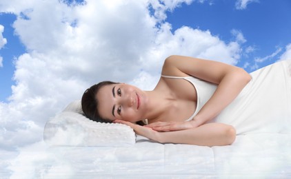 Woman lying on orthopedic pillow against blue sky
