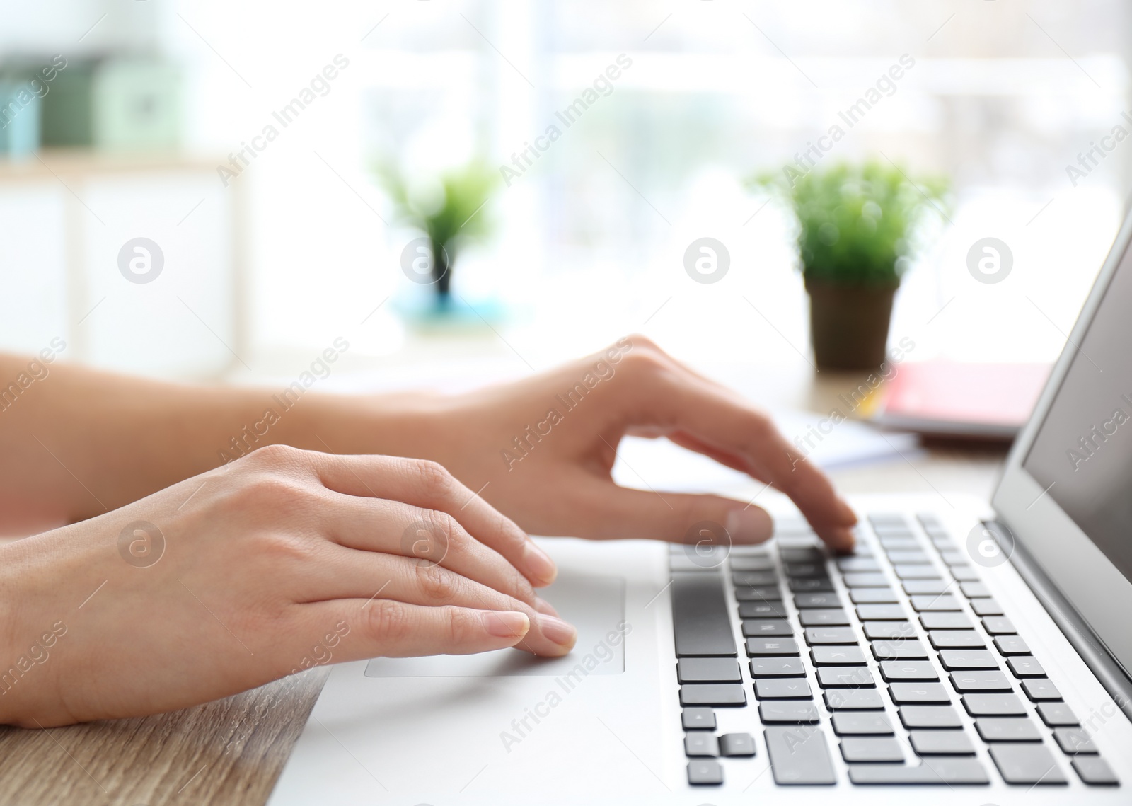 Photo of Young woman using laptop indoors, closeup