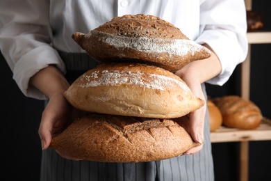 Photo of Baker holding loaves of bread indoors, closeup