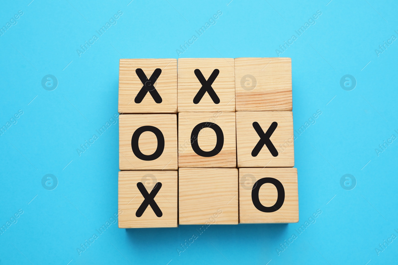 Photo of Tic tac toe cube set on light blue background, flat lay