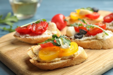 Photo of Wooden board with delicious tomato bruschettas on table, closeup