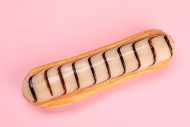 Delicious eclair covered with glaze on pink background, top view