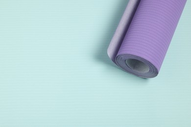 One violet wallpaper roll on light turquoise sample, top view. Space for text