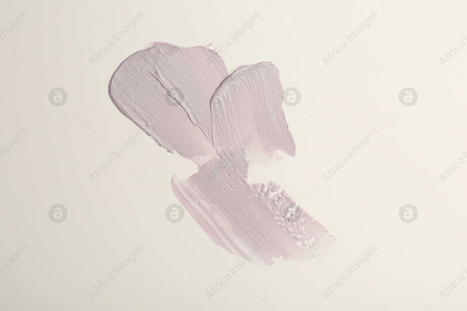 Photo of Strokes of purple color correcting concealers on white background, top view