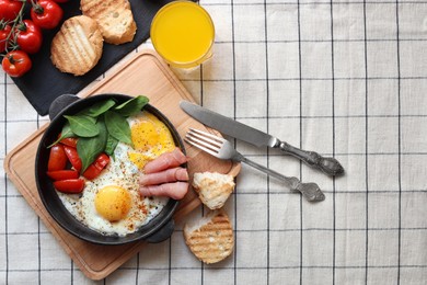 Photo of Delicious fried eggs with spinach, tomatoes and ham served on table, flat lay