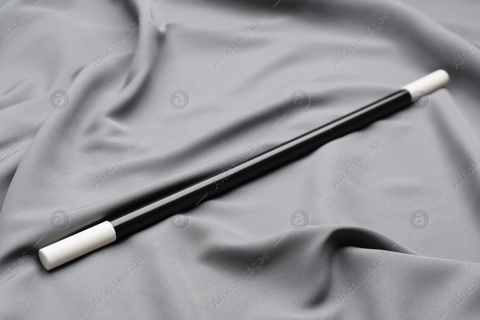 Photo of Beautiful black magic wand on grey fabric