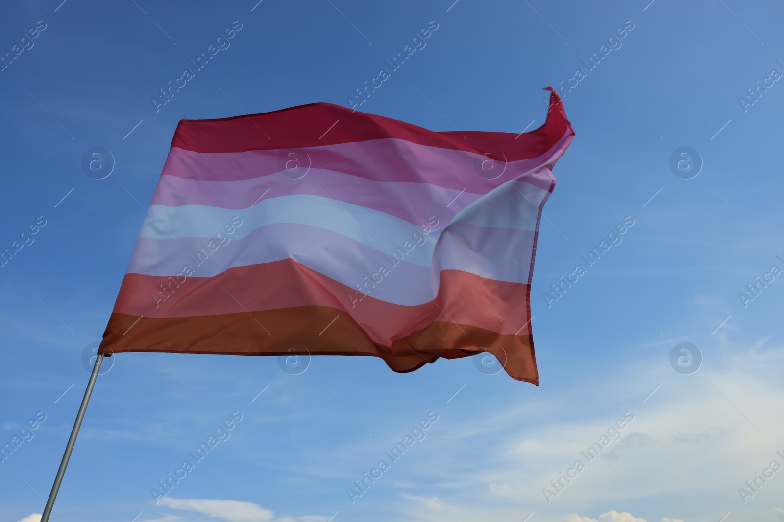 Photo of Bright lesbian flag fluttering against blue sky