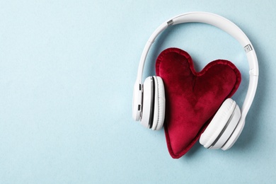 Photo of Modern headphones and red heart on turquoise background, flat lay with space for text. Listening love music songs
