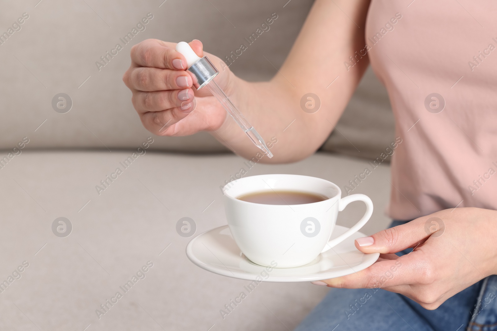 Photo of Woman dripping food supplement into cup indoors, closeup. Space for text