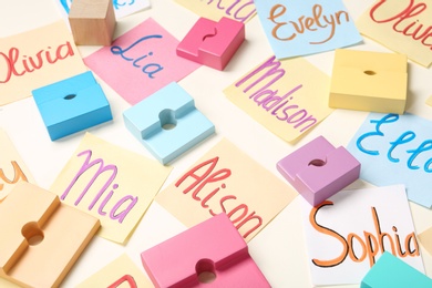 Photo of Colorful paper sheets with written different baby names and toys on beige background