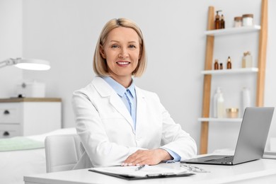 Photo of Portrait of happy dermatologist at white table in clinic