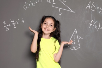 Photo of Little school child and mathematical formulas on grey background