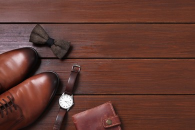 Stylish brown bow tie, shoes, wristwatch and wallet on wooden background, flat lay. Space for text
