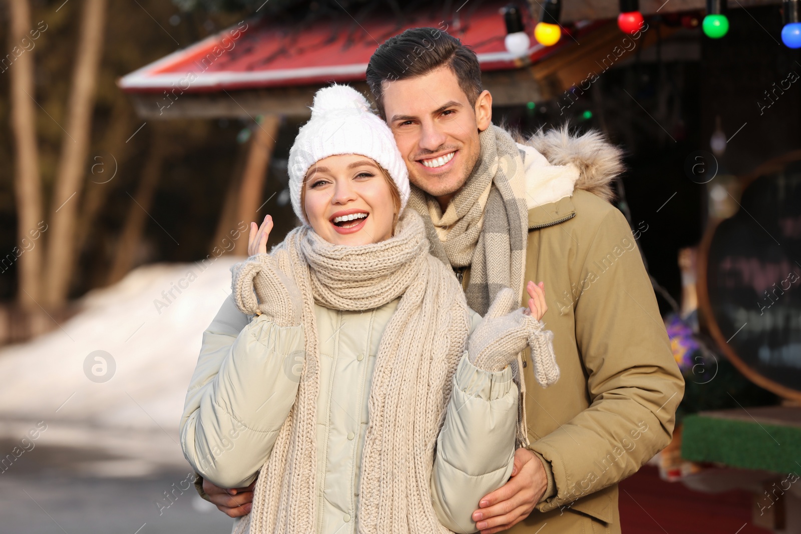 Photo of Happy couple in warm clothes at winter fair. Christmas season