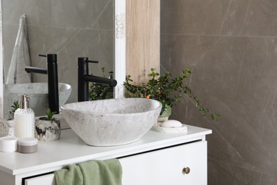 Photo of Chest of drawers with vessel sink, toiletries and houseplants in bathroom. Interior design