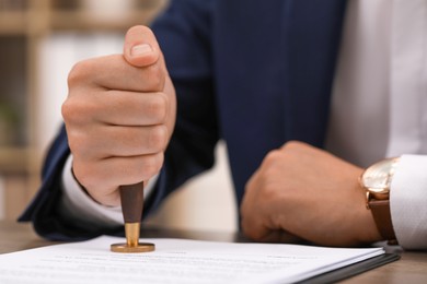 Photo of Man stamping document at table, closeup view