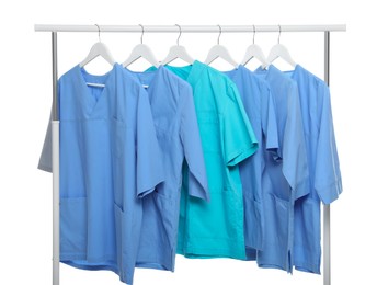 Light blue and turquoise medical uniforms on rack against white background