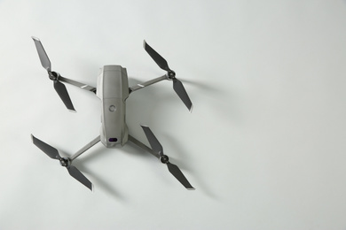 Photo of Modern drone with camera on light background, top view. Space for text