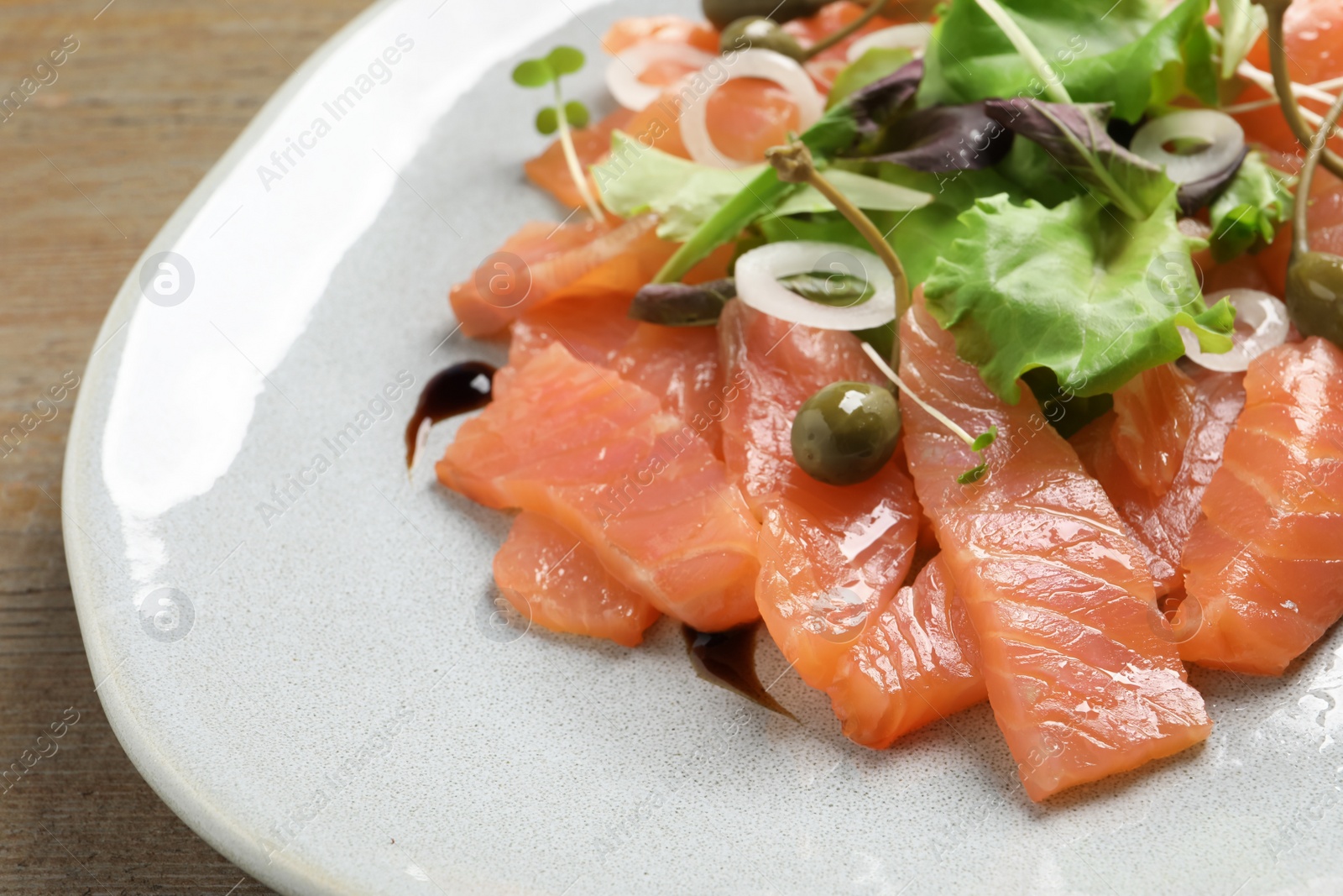 Photo of Delicious salmon carpaccio served on wooden table, closeup