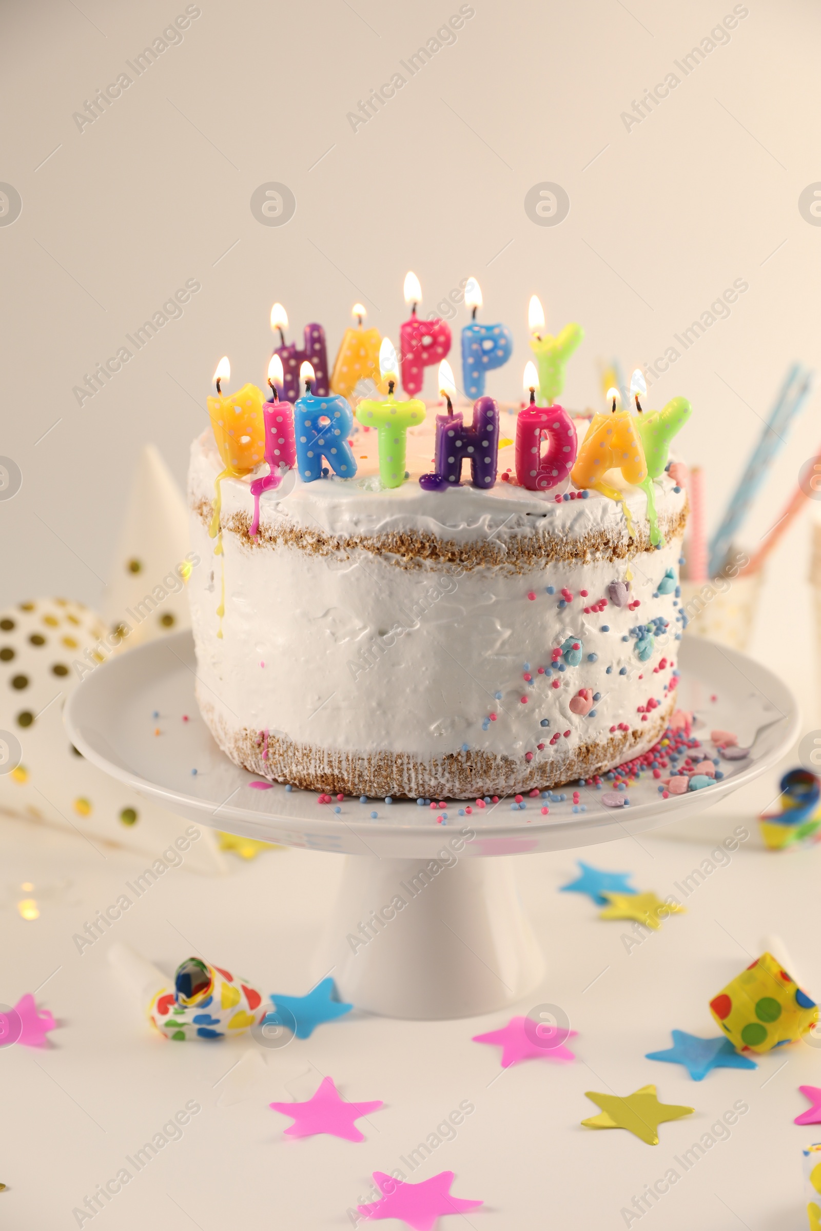 Photo of Tasty Birthday cake with burning candles and party decor on white table