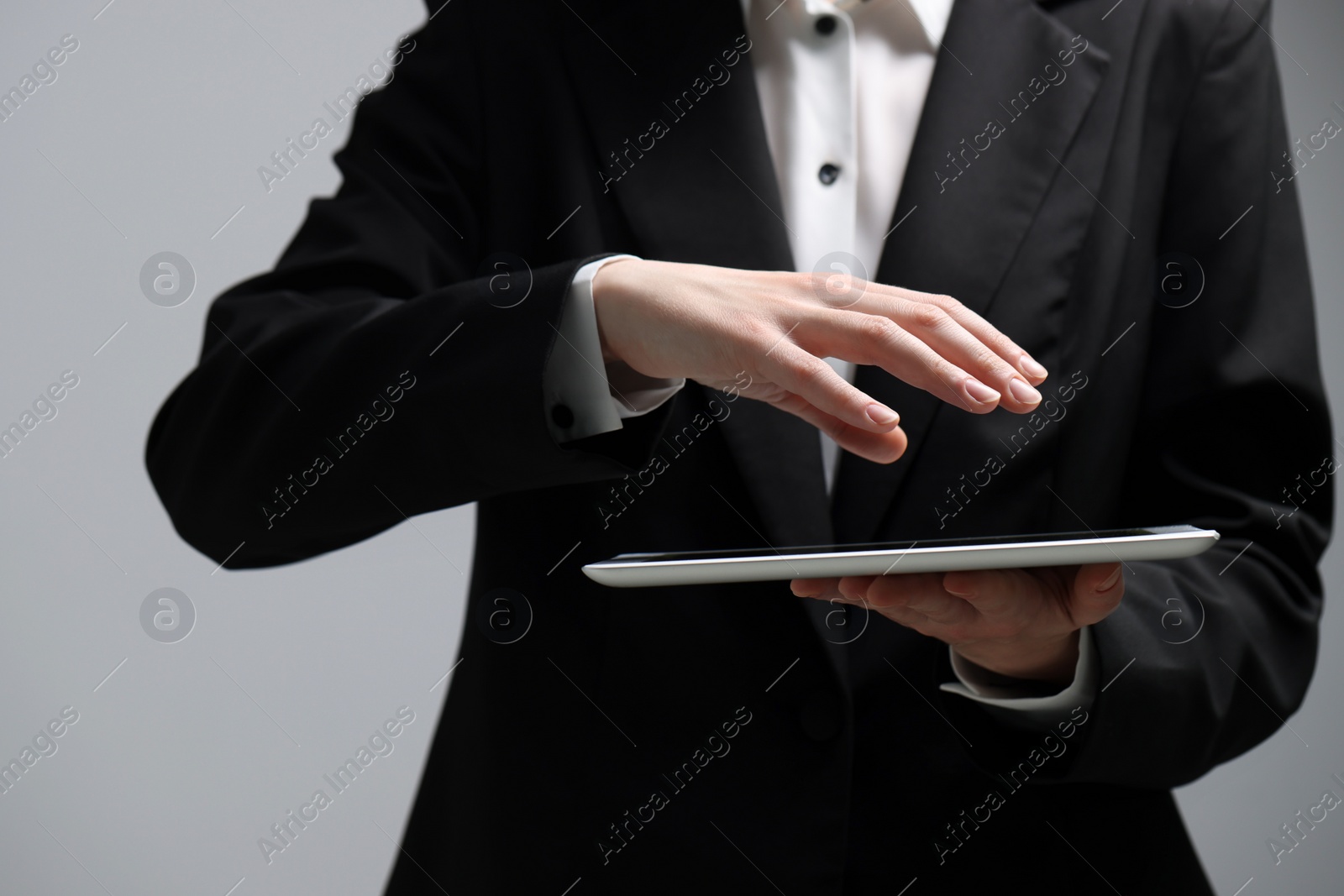 Photo of Closeup view of woman using modern tablet on grey background