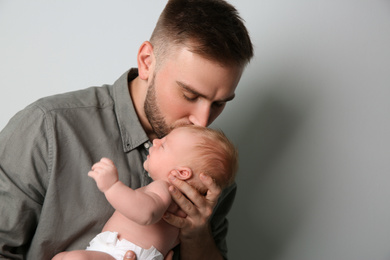 Photo of Father with his newborn son on light grey background