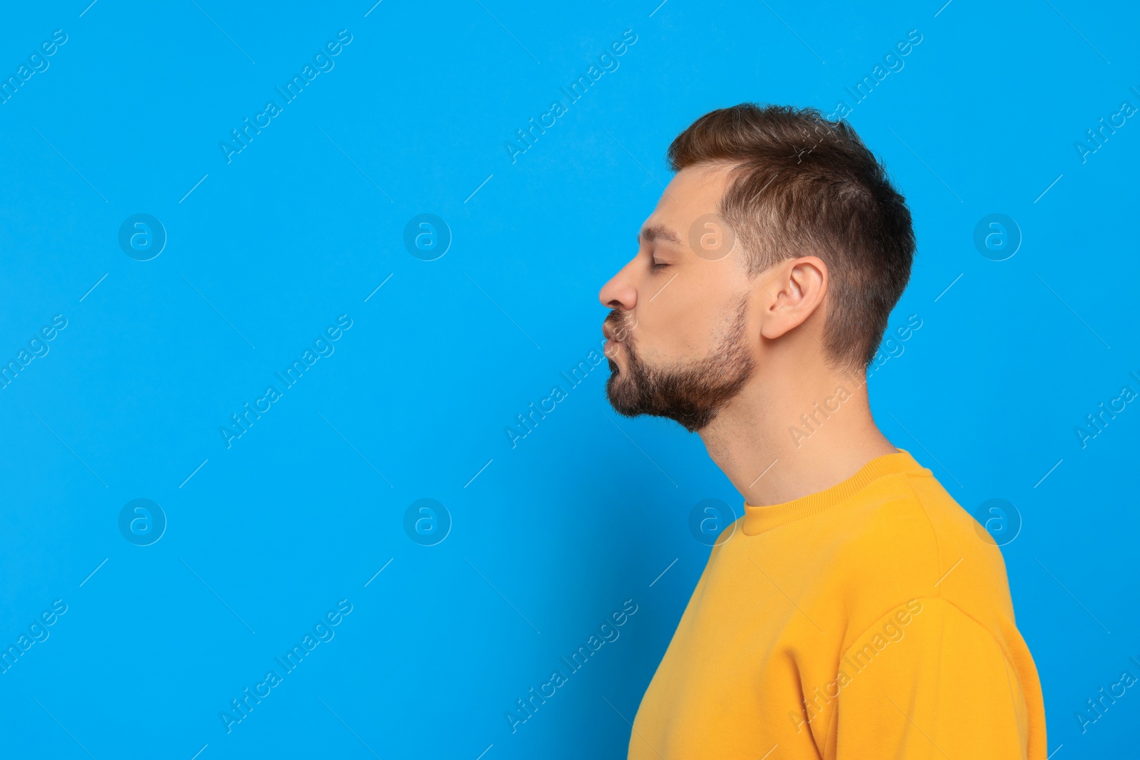 Photo of Handsome man blowing kiss on light blue background. Space for text