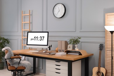 Stylish workplace with computer, houseplants and stationery on wooden desk near grey wall at home