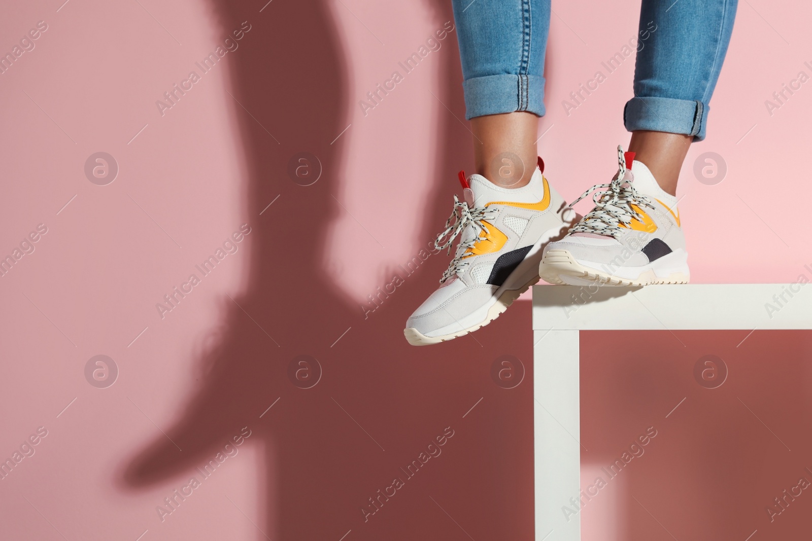 Photo of Woman in stylish sneakers near color wall, closeup. Space for text