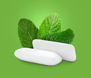 Menthol chewing gum pillows and mint leaves on bright green background