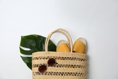 Stylish straw bag and summer accessories on white background, flat lay