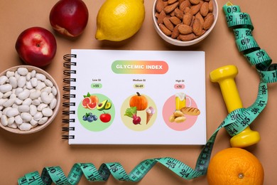 Image of Information about grouping of products under their glycemic index. Notebook, measuring tape, dumbbell, beans, almonds and fruits on light brown background, flat lay