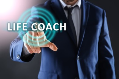 Life coaching concept. Businessman touching virtual screen on dark background, closeup