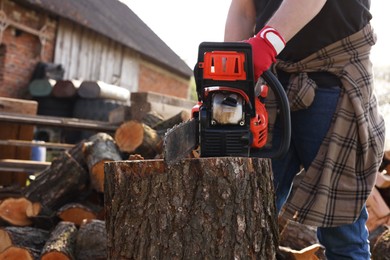 Photo of Man sawing wooden log outdoors, closeup view