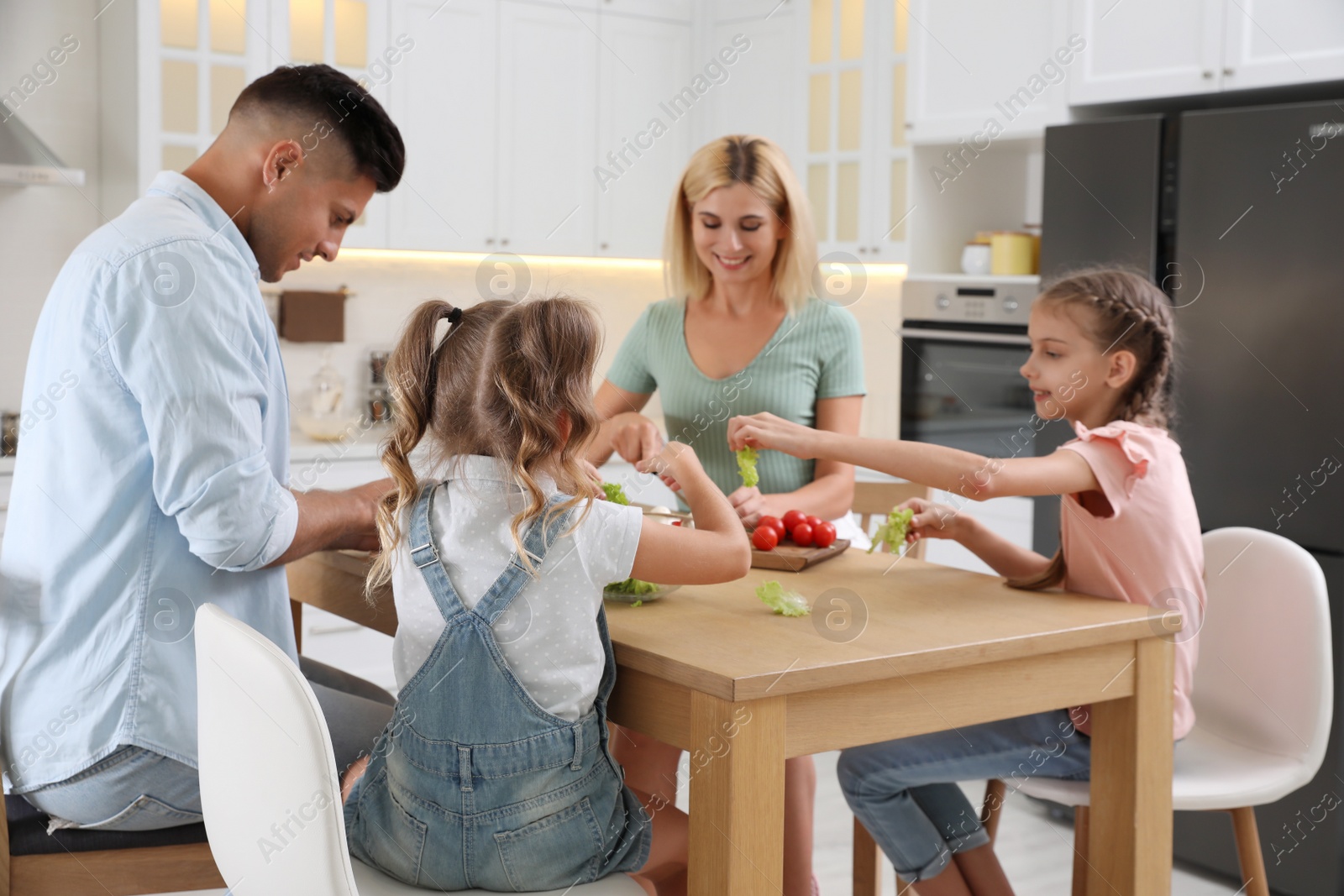 Photo of Happy family cooking together at table in modern kitchen