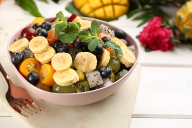 Photo of Delicious exotic fruit salad on white table, closeup
