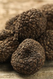 Photo of Heap of black truffles on wooden table, closeup