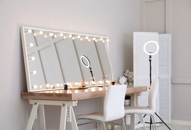 Photo of Modern mirror with light bulbs on dressing table in makeup room