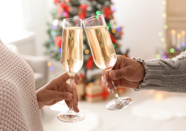 Photo of Happy young couple with glasses of champagne celebrating Christmas at home