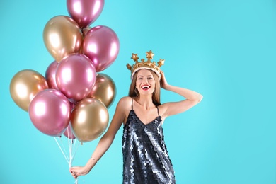 Photo of Young woman with crown and air balloons on color background