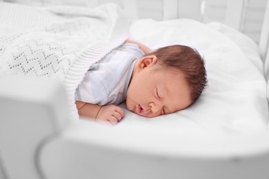 Photo of Cute newborn baby sleeping under plaid in crib