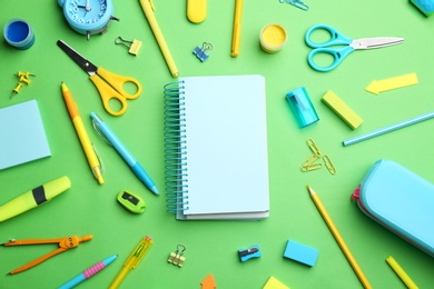 Different bright school stationery and blank notebook on light green background, flat lay. Space for text