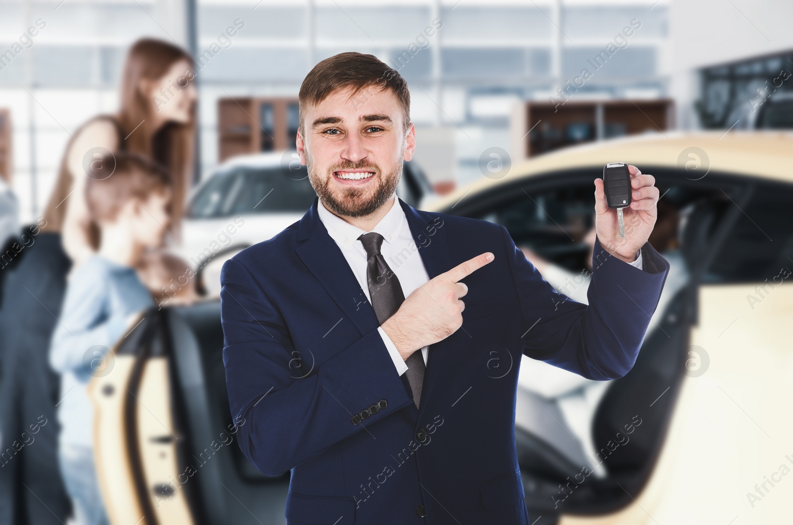 Image of Happy salesman with key in car salon