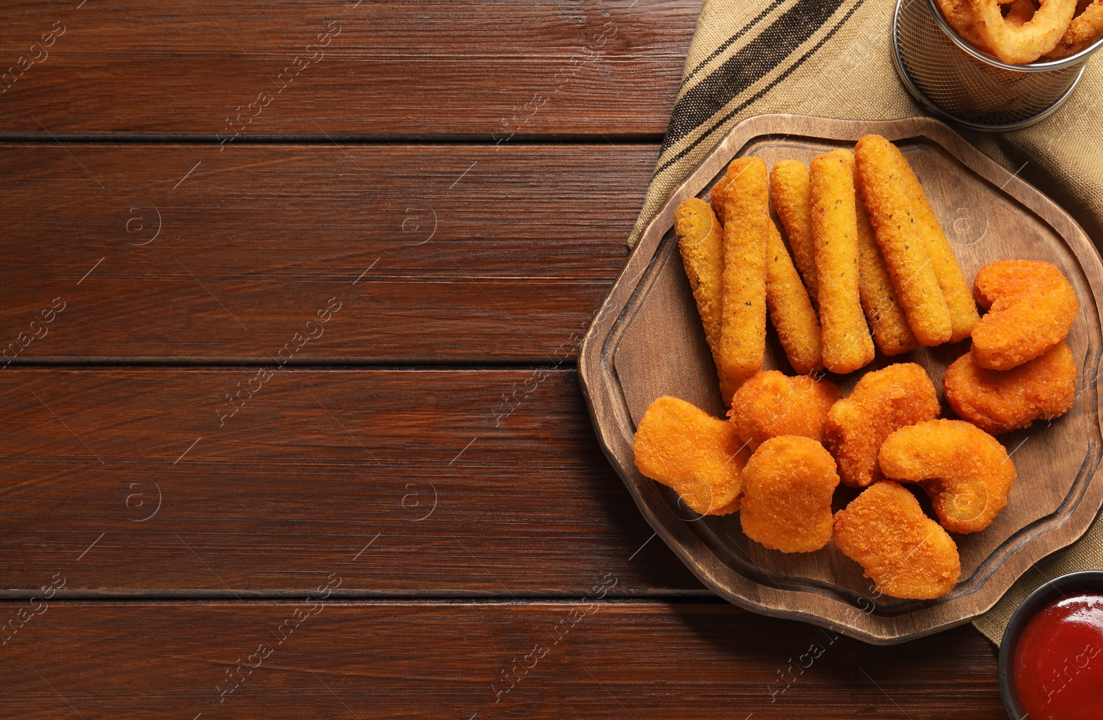 Photo of Tasty ketchup, chicken nuggets and cheese sticks on wooden table, flat lay. Space for text